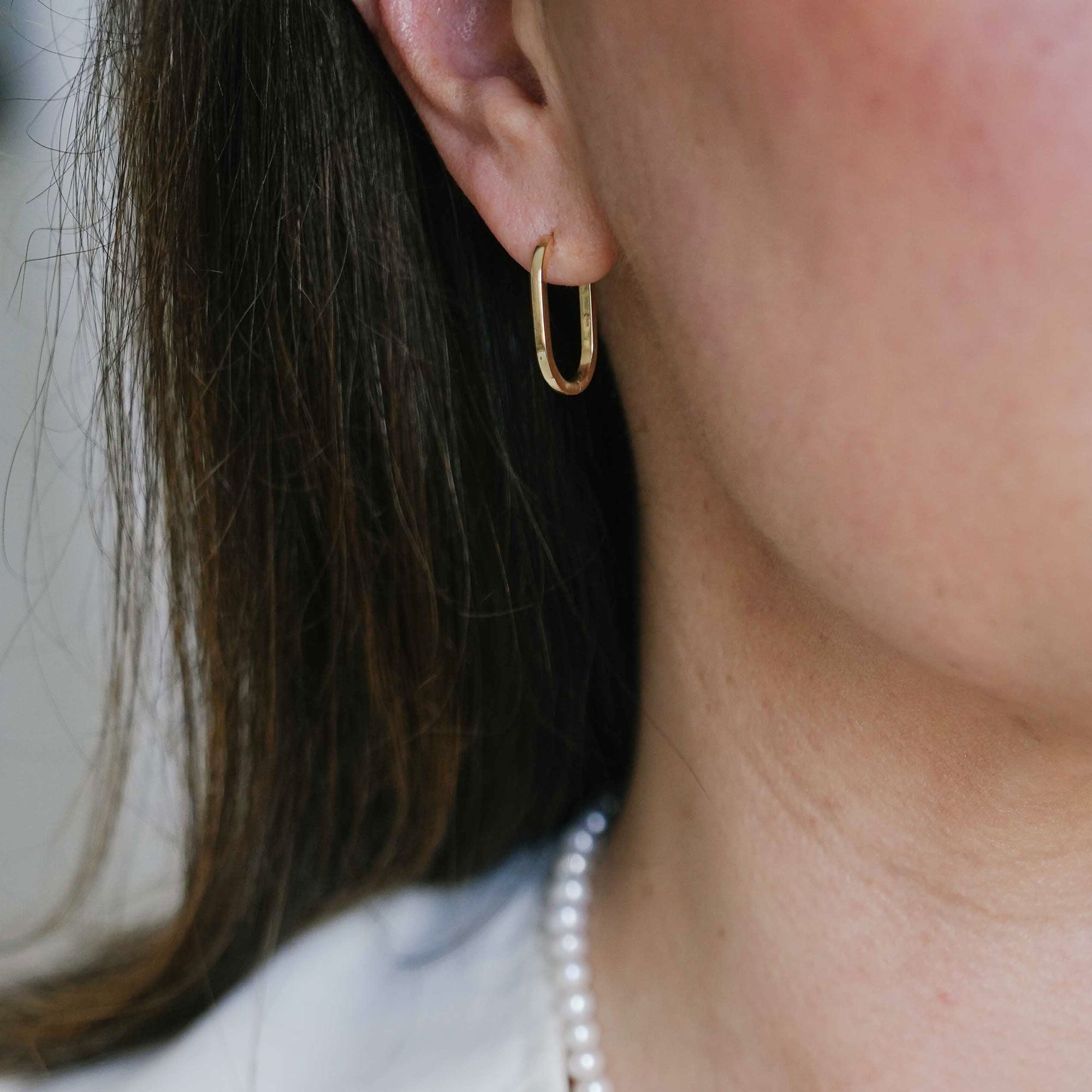 Long oval huggie hoops on ear