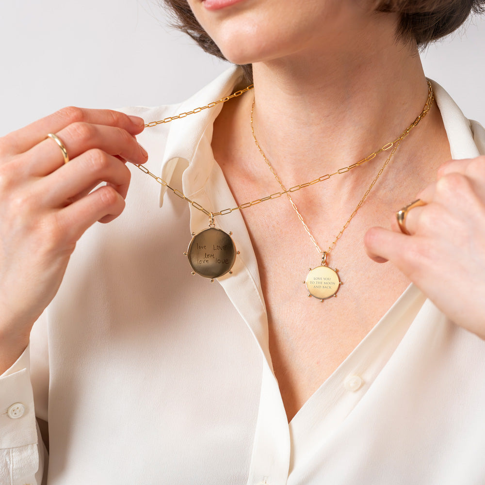 model holding up the large celestial medallion on a paper clip chain necklace