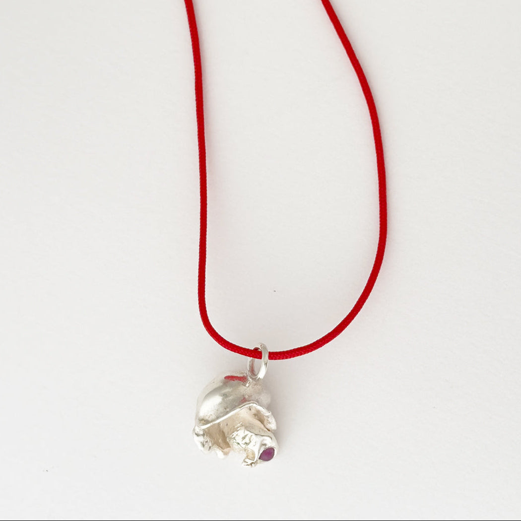A silver elephant pendant necklace on a vibrant red cord, photographed against a plain white background.