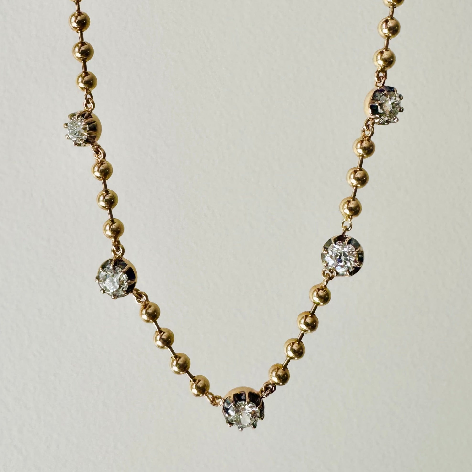 Gold necklace with embedded crystals on a light gray background