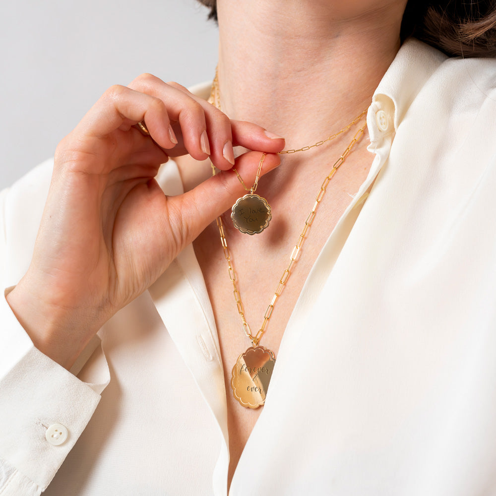 Model holding a necklace with the medium scalloped medallion