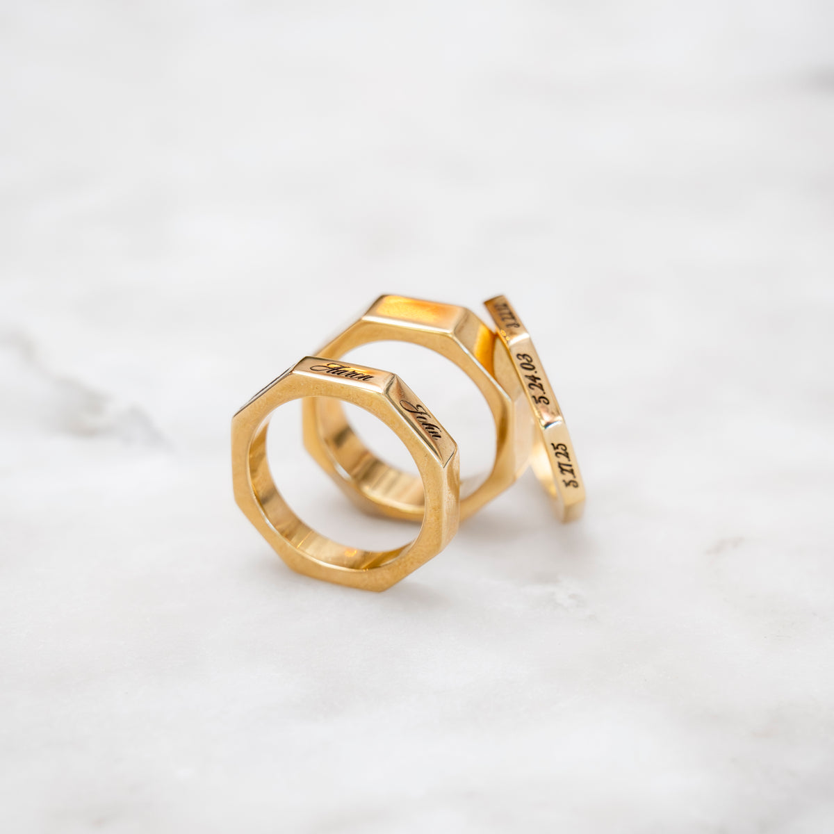 Three gold octagonal rings with text engraved on them