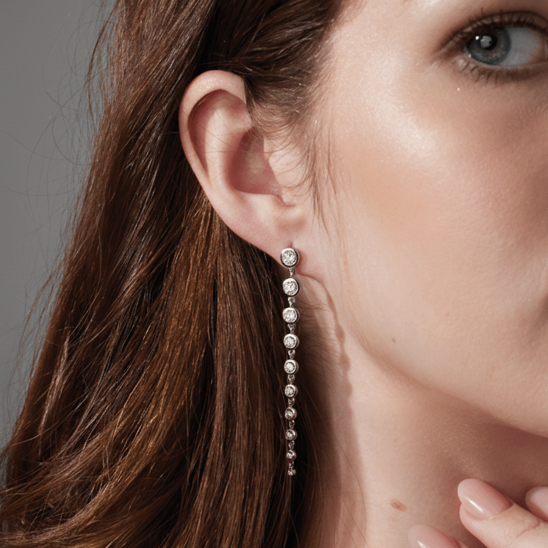 Woman wearing 14K white gold diamond earrings against a pink background